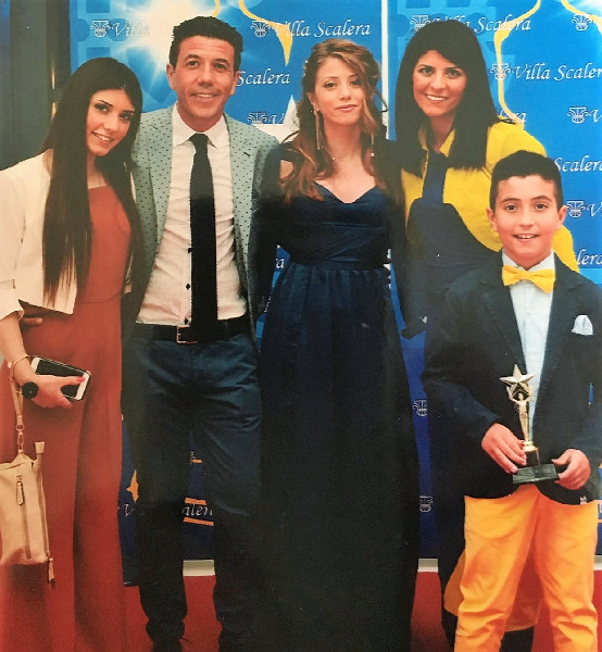 1 man 3 women and one teen age boy holding a award posing for the camera on a red carpet.